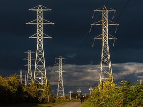Cyclists ride past hydro towers against a dark blue sky.