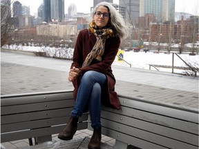 Bochra Manai sits on a park bench with the Montreal skyline behind her