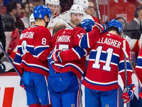 Montreal Canadiens' Alex Newhook is helped off the ice by teammates Mike Matheson and Brendan Gallagher
