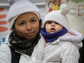 Ileana Olivas holds an infant in her arms, both bundled up for the cold