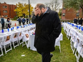 An emotional man holds his hand over his face as he stands near an empty Shabbat table.