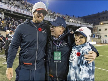 Alouettes general manager Danny Macocia hugs head coach Jason Maas, left, and Maas's son Bear following Canadian Football League East Division semifinal playoff game against the Hamilton Tiger-Cats in Montreal on Saturday, Nov. 4, 2023.