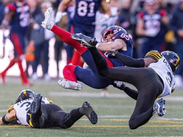 Alouettes receiver Tyler Snead is tackled by Hamilton Tiger-Cats Stavros Katsantonios, left, and Kenneth George Jr. during second half of Canadian Football League East Division semifinal playoff game against the Hamilton Tiger-Cats in Montreal on Saturday, Nov. 4, 2023.
