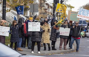 A group of striking teachers holds up signs at an intersection