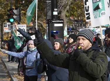 A man blows a whistle while standing on a picket line