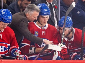 Martin St. Louis points to something in Juraj Slafkovsky's hand on the Canadiens bench