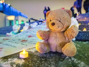 A stuffed animal and a candle sit next to a banner placed outside at night