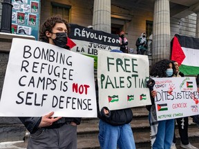 People hold signs on a building's steps criticizing the Israeli government