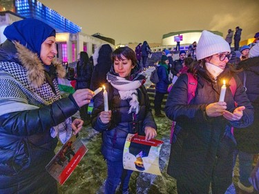 Women gathered in a crowd light candles