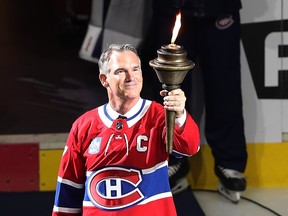 Pierre Turgeon, in a Canadiens jersey, holds up a lit torch on the ice