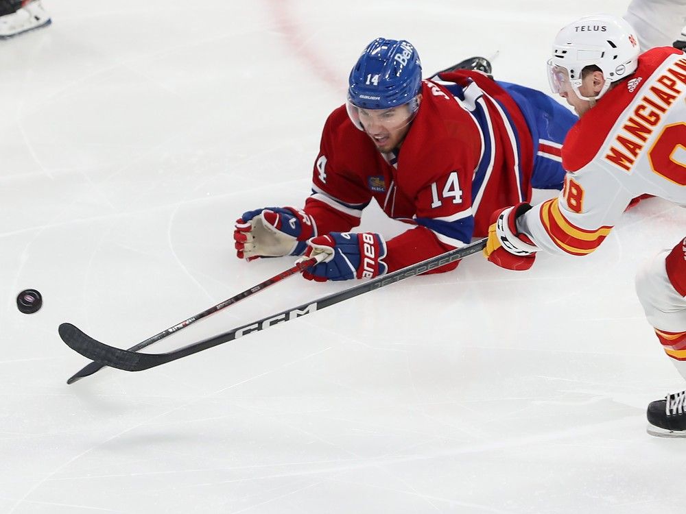 Nick Suzuki reaches for the pick while lying on the ice