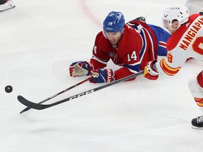 Nick Suzuki reaches for the pick while lying on the ice
