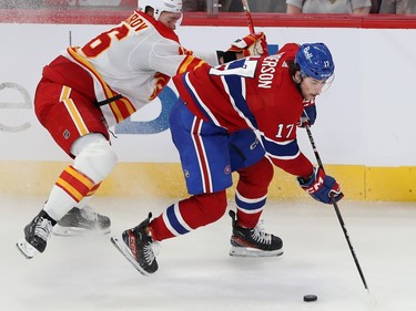 Montreal Canadiens' Josh Anderson skates with the puck along the boards with Calgary Flames' Nikita Zadorov (16) right behind him