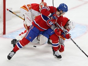 Three players in front of the Calgary net with the puck just outside the crease