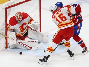 Calgary Flames goaltender Jacob Markstrom stops the puck in front of Montreal Canadiens' Jesse Ylonen (56) and Calgary Flames' Nikita Zadorov (16)