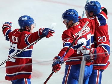 Three Canadiens players embrace on the ice