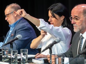 Valérie Plante rolls up her sleeves between two men at a table