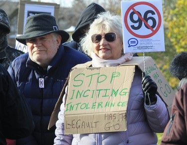 A woman wears a sign reading Stop Inciting Intolerance at a Bill 96 protest.