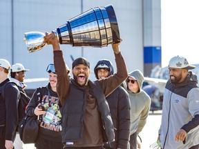 Dishon McNary hoists the Grey Cup over his head with other players nearby