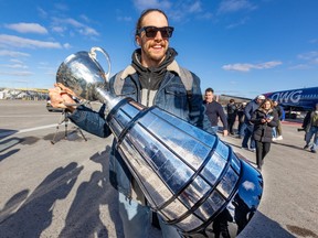 Marc-Antoine Dequoy of the Montreal Alouettes carries the Grey Cup on the tarmac at Mirabel airport after the team's arrival on Nov. 20, 2023.