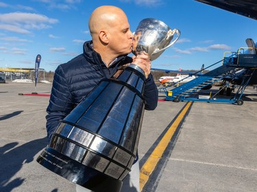 Mark Weightman kisses the Grey Cup on an airport tarmac
