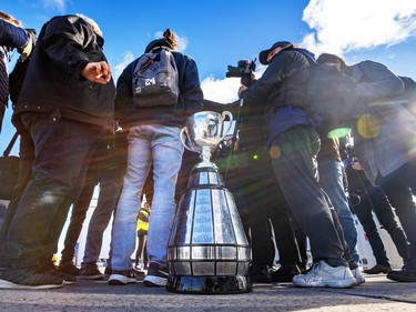 The Grey Cup sits on the ground behind several people in a circle outside