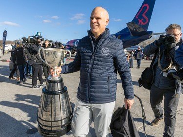 Mark Weightman carries the Grey Cup by the neck walking away from a plane