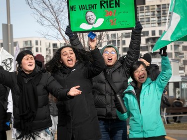 Four people yell excitedly, one holding a sign with François Legault's face and some writing on it