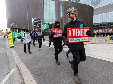 Two men hold signs reading 'À vendre — Condition: Maganée / Jobs sous-payées'