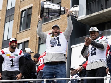Kristian Matte hoists the Grey Cup above his head while riding on the top of an open-roof double-decker bus