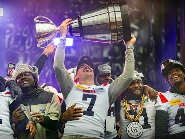 Cody Fajardo smiles and looks up at the Grey Cup he's holding above his head