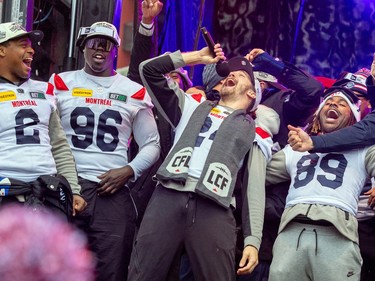 Marc-Antoine Dequoy leans back as he yells into a microphone on stage with fellow Alouettes players