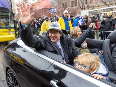 Pierre-Karl Péladeau rides in a convertible with his family waving at fans during a parade