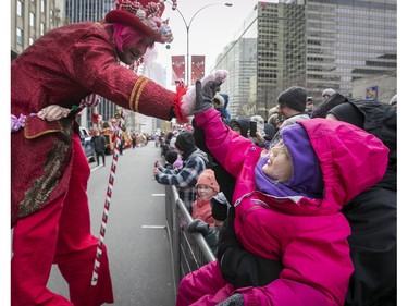 Three-year-old Abby Dupuis-Monière gets a highfive from a clown during the Montreal Santa Claus parade on Saturday, Nov. 25, 2023.
