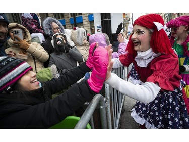 Clowns give out high-fives to the crowd as they take part in the Montreal Santa Claus parade on Saturday, Nov. 25, 2023.
