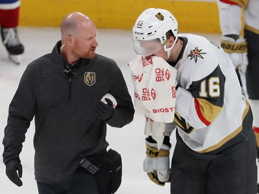 Vegas Golden Knights' Pavel Dorofeyev holds a towel to his mouth with a staff member beside him