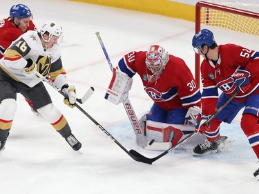 Montreal Canadiens goaltender Cayden Primeau has the puck on his stick as two players are on either side of him