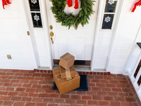 Three parcels are stacked in front of a door with a wreath.