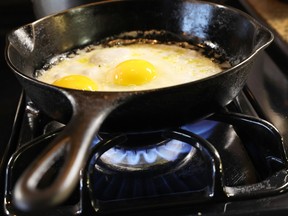 Eggs cook in a cast iron pan over flames on a natural gas-burning stove