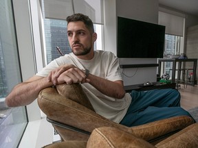 James Pantemis reclines on a chair and looks out the living room window of a modern condo in a high-rise building downtown