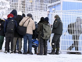 Finnish Border Guards check the documents of the arriving migrants at the international border crossing at Salla