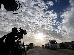 Media representatives work as a truck carrying humanitarian aid from the United Nations Relief and Works Agency for Palestine Refugees (UNRWA) arrives at the Egyptian side of the Rafah border crossing with the Gaza Strip on November 22, 2023, amid ongoing battles between Israel and the Palestinian militant group Hamas. (Photo by Khaled DESOUKI / AFP)