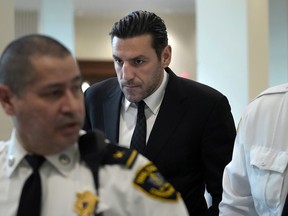 Bruins forward Milan Lucic is flanked by court officers as he arrives at Boston Municipal Court on Tuesday for his arraignment on an assault charge in connection with his arrest over the weekend after his wife called police to their home.