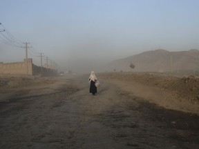 A woman begs in the middle of the road on the outskirts of in Kabul, Afghanistan, Friday, June 16, 2023.