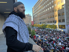 A man on a balcony overlooking a protesting crowd