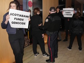 Protesters are escorted out of the Four Seasons Hotel by the police after interrupting the Scotiabank Giller Prize ceremony in Toronto, on Monday, Nov. 13, 2023.