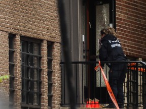 A police officer works at Yeshiva Gedola school on Deacon Road in the in the Notre-Dame-de-Grâce--Côte-des-Neiges borough of Montreal on Sunday, Nov. 12, 2023, where gunshots were fired early Sunday morning. A bullet impact can be seen on the front door.