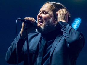 Karl Tremblay sings into a microphone on stage at a concert