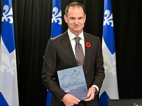 A man holding a document in front of a row of Quebec flags