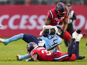 Alouettes linebacker Darnell Sankey (1) and defensive back Reggie Stubblefield combine to tackle Argonauts running-back Saturday afternoon in Toronto.